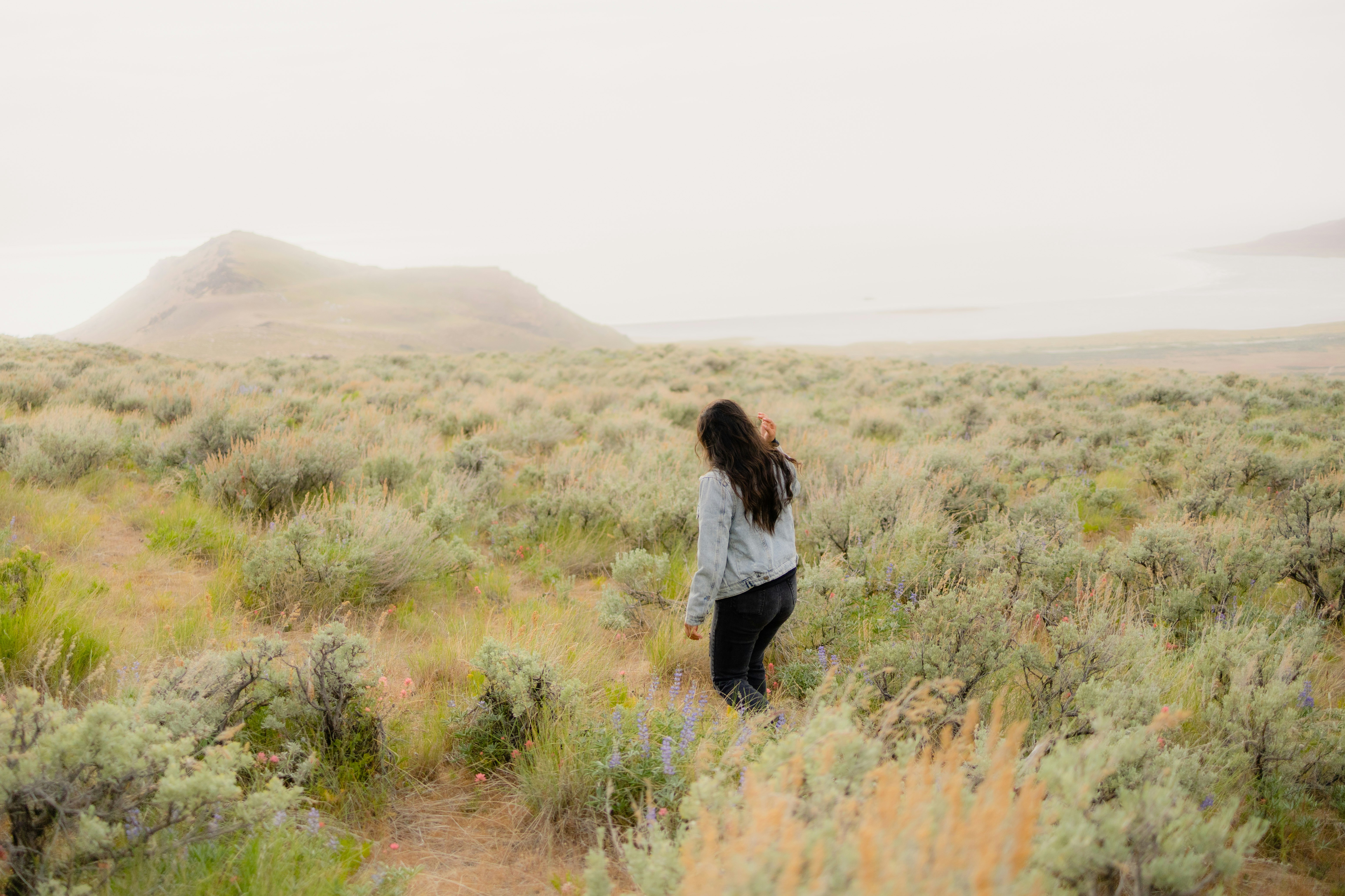 woman in white long sleeve shirt and black pants standing on brown grass field during daytime